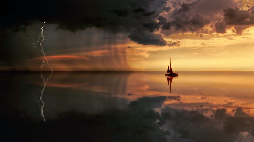 océan au moment du coucher de soleil avec un bateau qui s'avance vers un orage