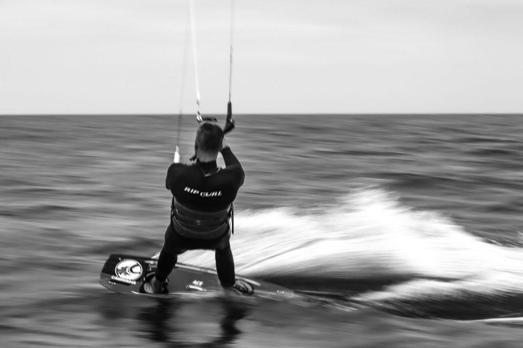 Une photo en noir et blanc d'un kitesurfeur qui navigue à Fuerteventura.