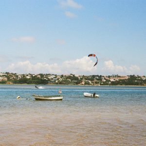 Photo argentique de la lagune d'obidos. Un kitesurfeur navigue sur le spot, deux petites embarcations sont devant lui.