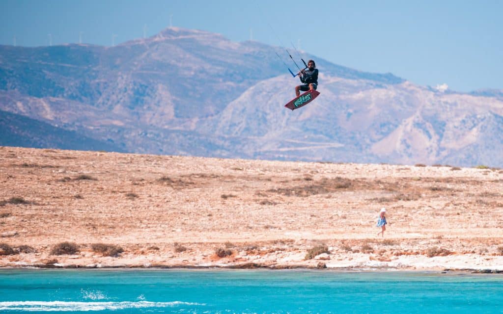 kitesurfeur en grèce qui effectue un saut au dessus de l'eau turquoise